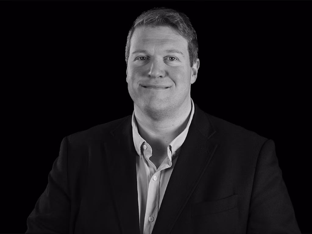 Robin Hartley, Partner at Level, Employee Ownership Professional headshot of Robin Hartley in black and white, wearing a suit jacket and button-down shirt